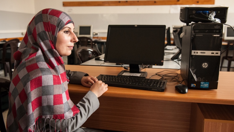 A teacher sitting in a classroom, near Ramallah